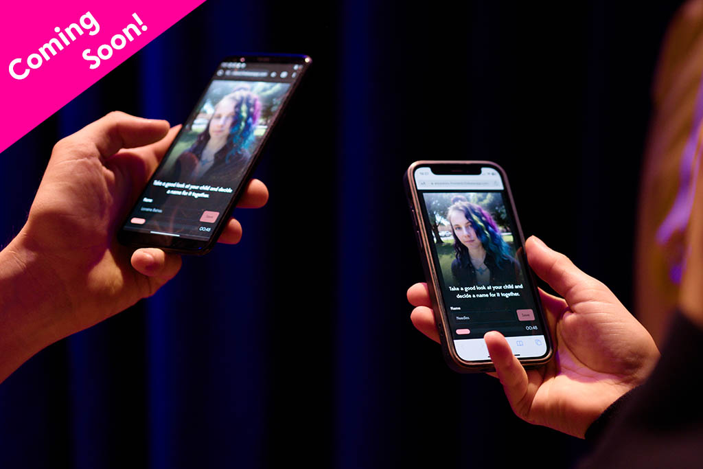 The hands and smartphones of two participants of Ancestors; on the smartphone screen is an image of an unknown person, and a pink banner in the top left corner reading "Coming soon!"