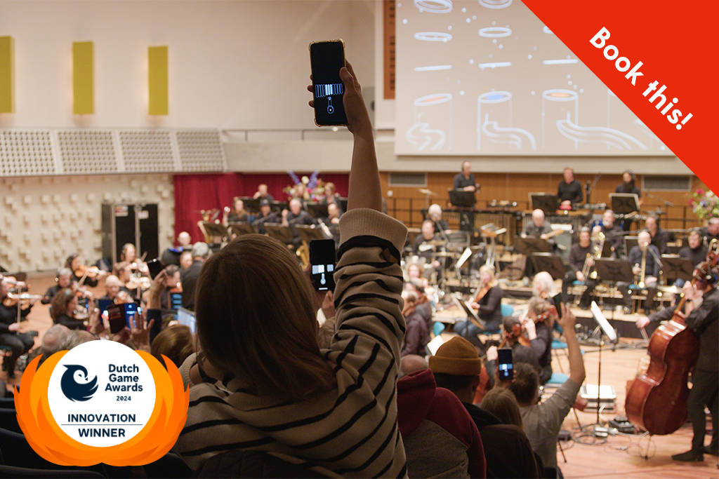 Audience members holding up their phones during a game within The Score, and an orchestra playing in the background, with a red banner in the top right corner reading, "Book this!"